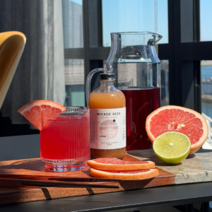 Under My Ella mocktail with a bottle of Wicked Bess shrub